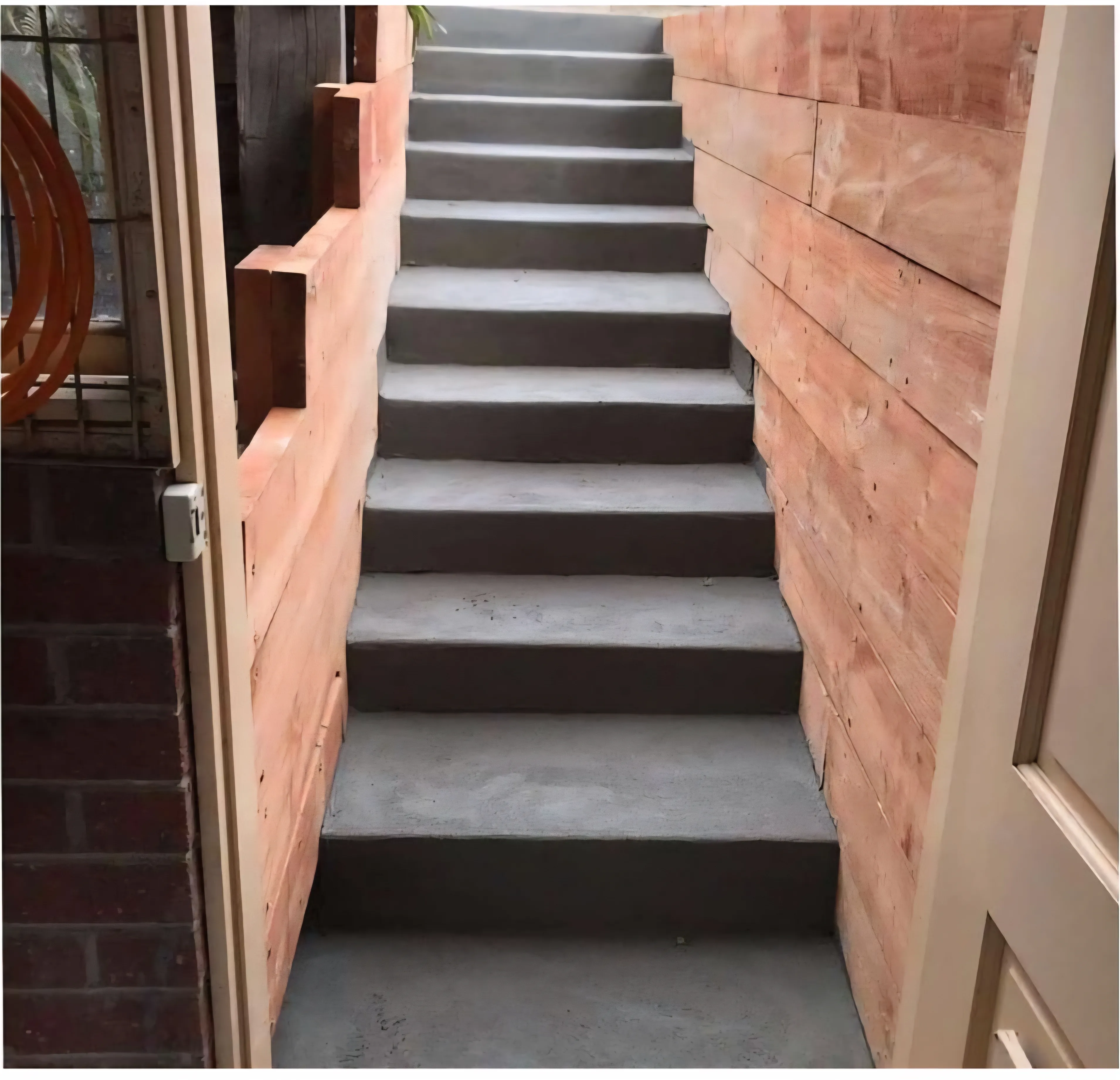 New concrete steps rising between timber sleeper retaining walls at a home entrance