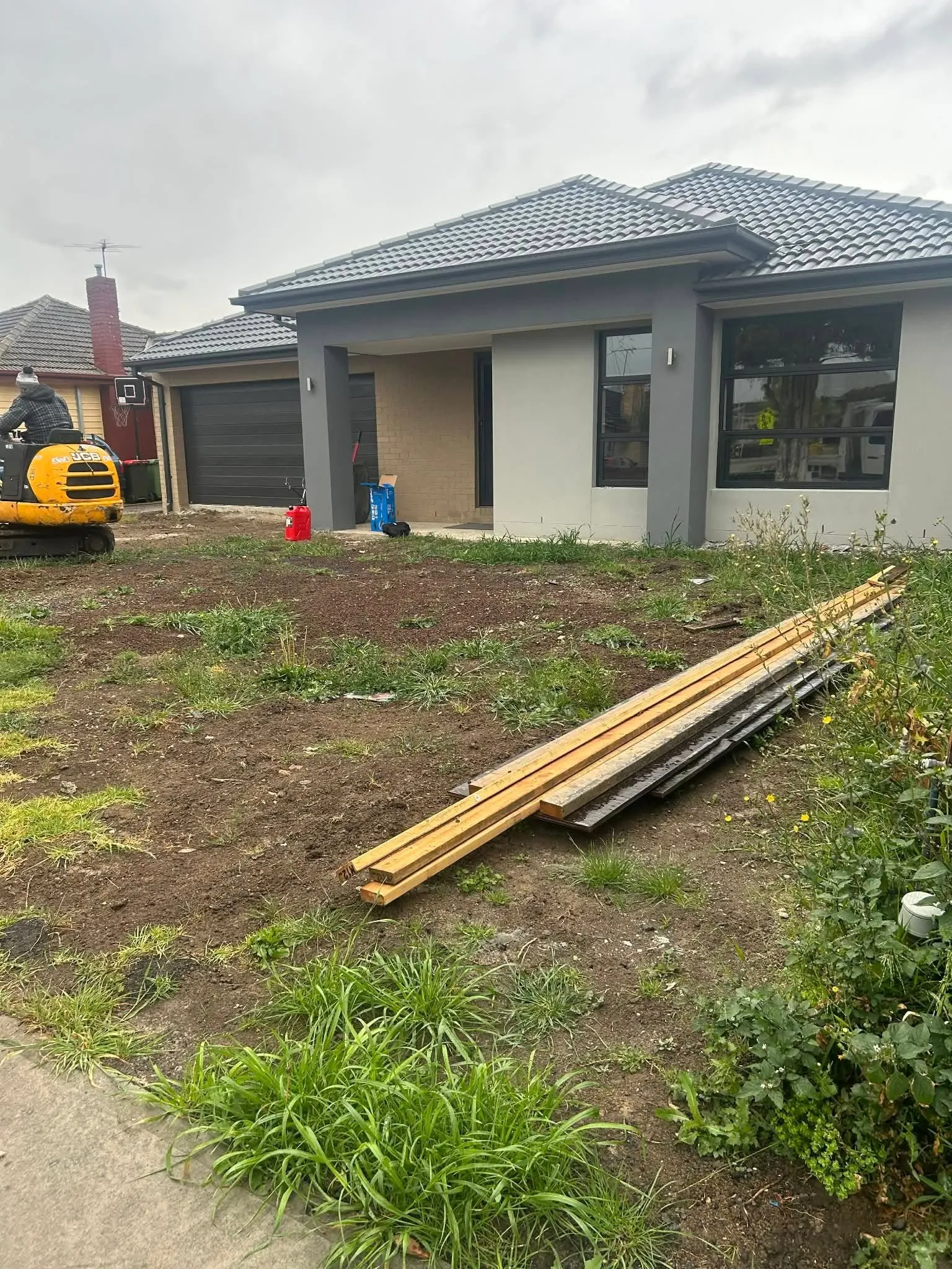 Front yard during excavation and site prep, with an excavator on a cleared block
