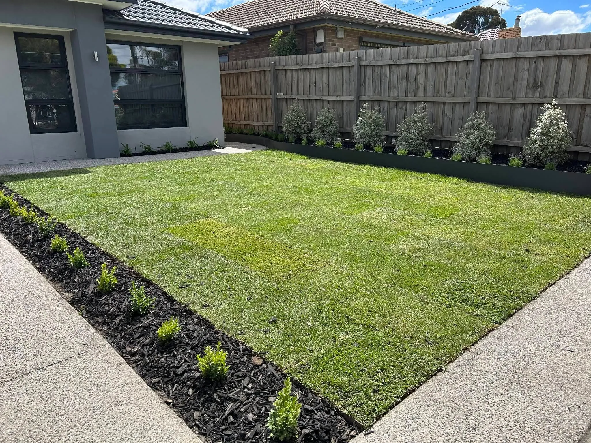 Completed front-yard makeover with freshly laid turf, mulched garden beds and young shrubs